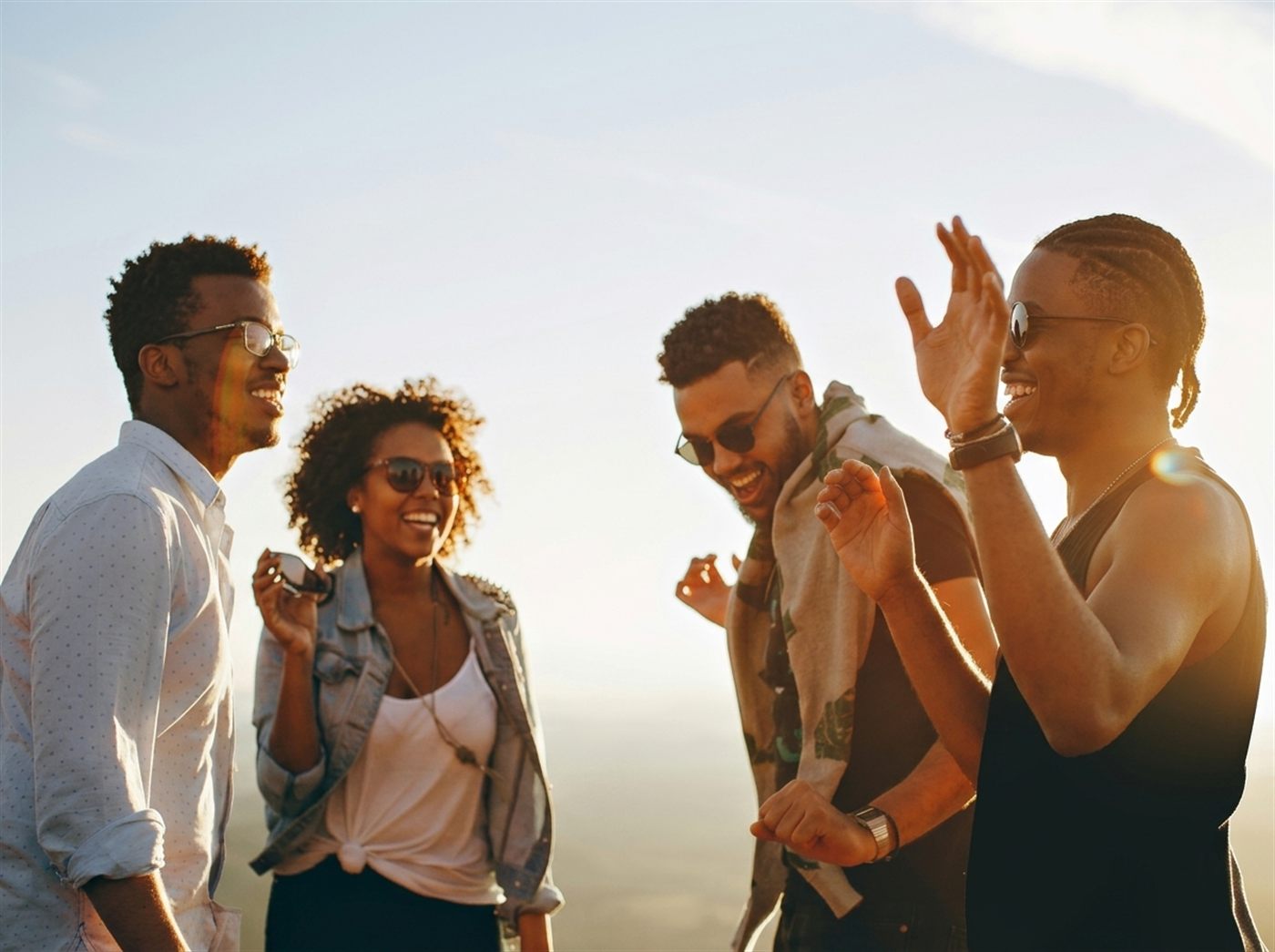 Four African friends laughing together outdoors at golden hour