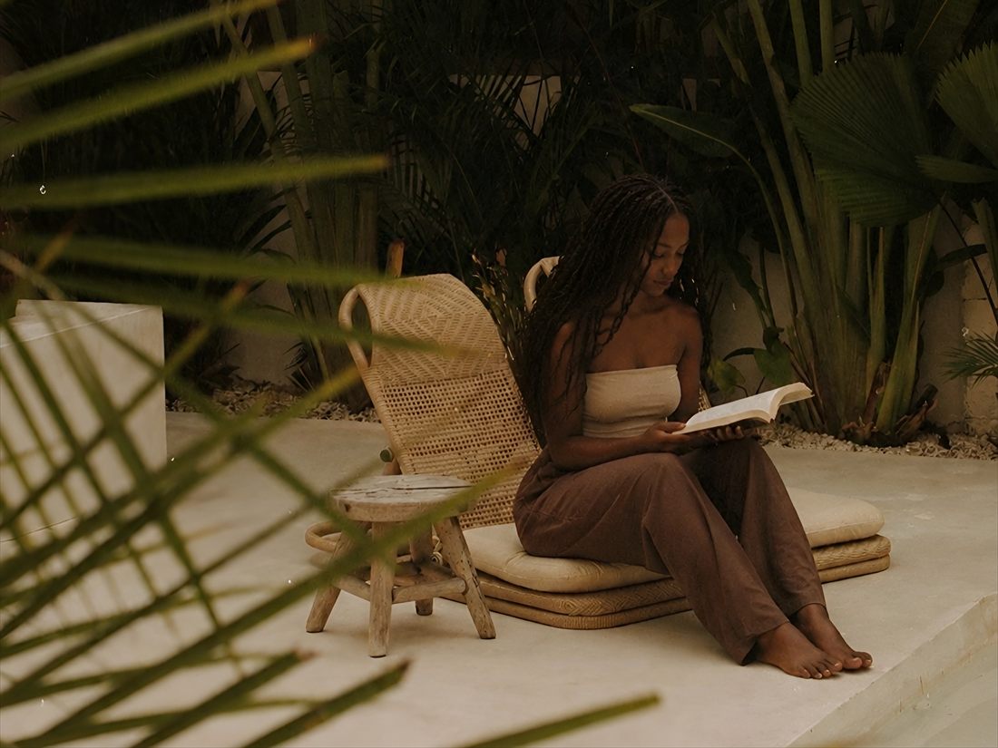 A woman reading on a villa terrace surrounded by tropical planting in Bali